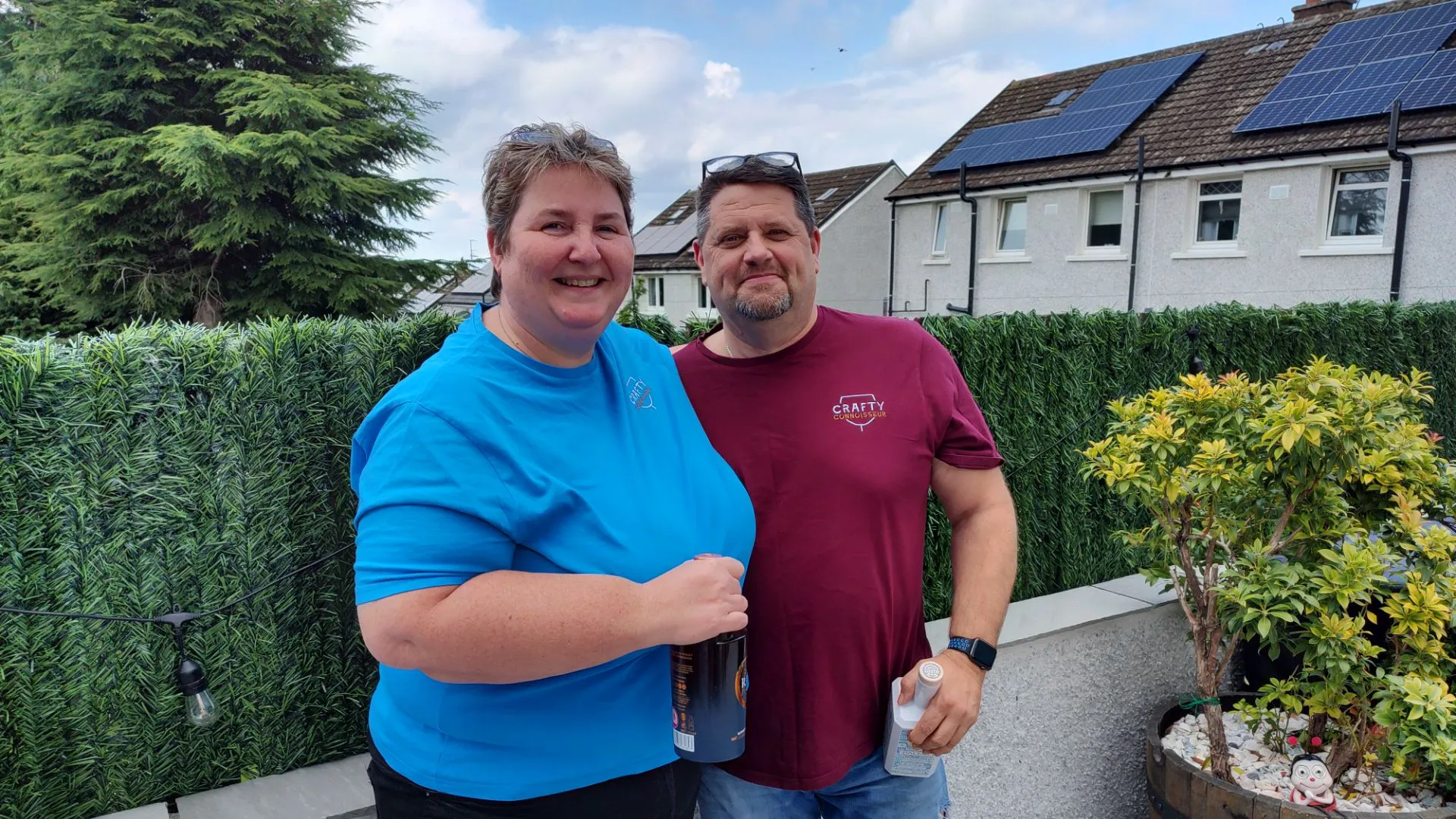 Two people standing in front of a fence with solar panels.