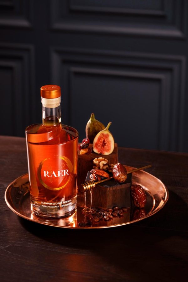 A bottle of RAER Blended Scotch Whisky Pedro Ximénez Expression with figs and nuts on a tray.