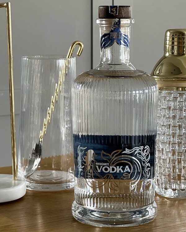 A bottle of Orkney Vodka sits on a table next to other items.