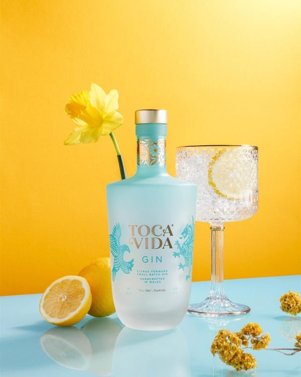 A bottle of Toca Vida Gin with lemons and flowers.